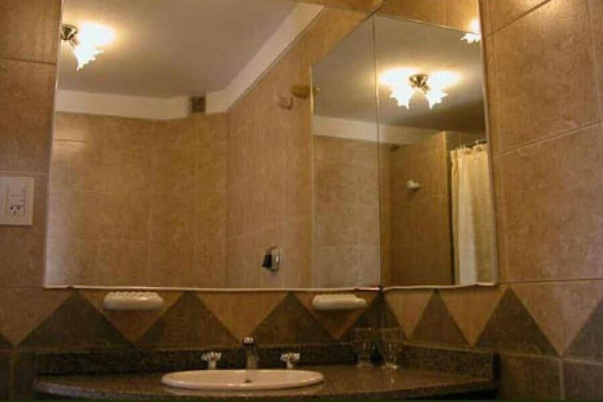 Une salle de bain avec un grand miroir, un lavabo et une douche.