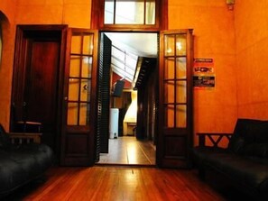 Una habitación con pisos de madera, una escalera y una puerta que da a otra zona.