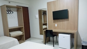 Une chambre avec deux lits, un bureau avec une chaise, une télévision et un mini-réfrigérateur.