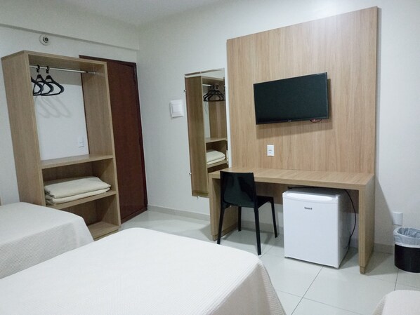 A room with two beds, a desk with a chair, a TV, and a mini-fridge.