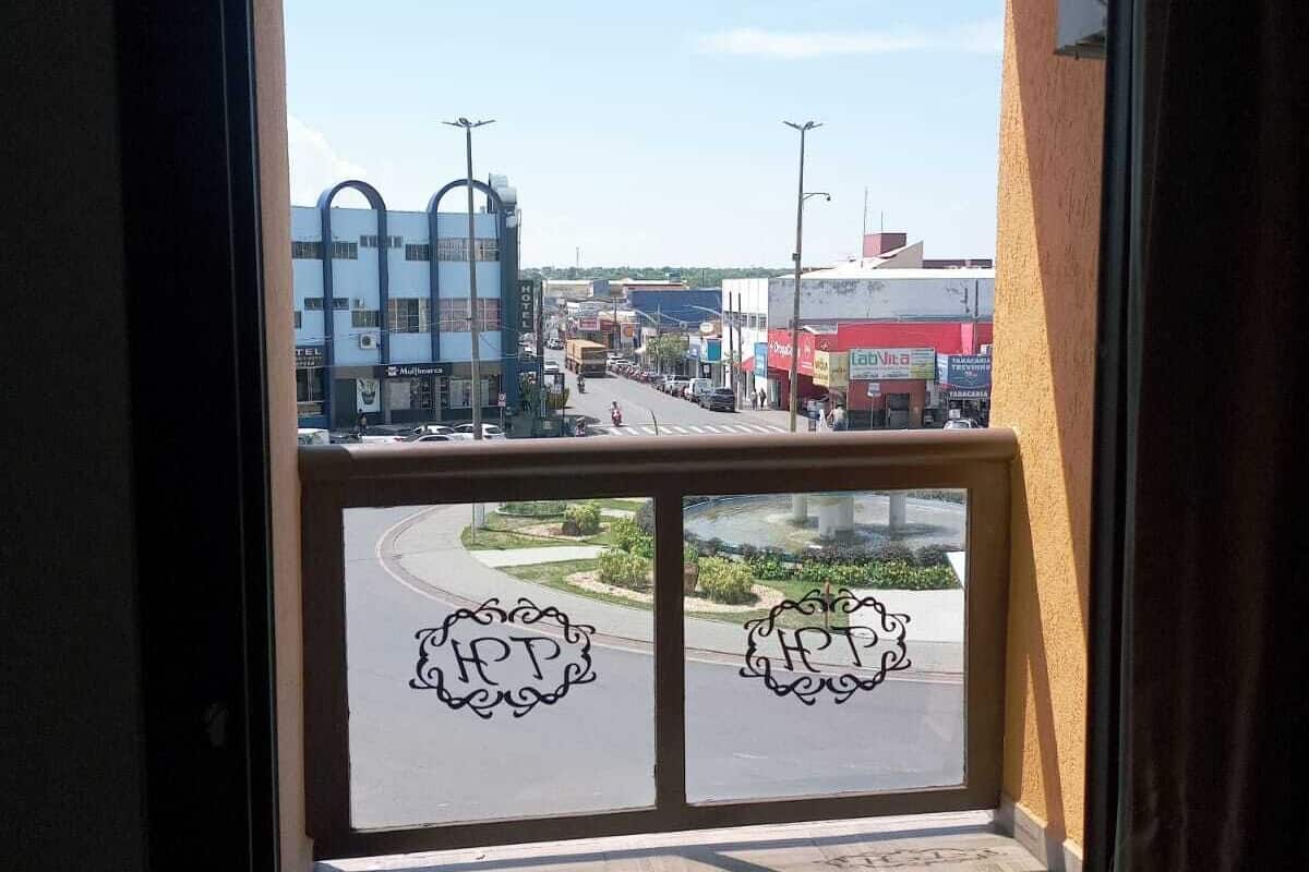 Un balcon donnant sur une rue, un hôtel et un immeuble sur lequel on peut lire l’inscription « Hôtel ».