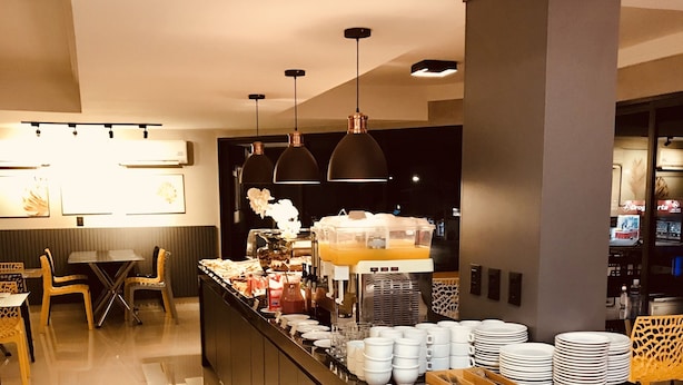Un espace moderne dédié au petit-déjeuner, avec un bar central, des sièges et une machine à café.