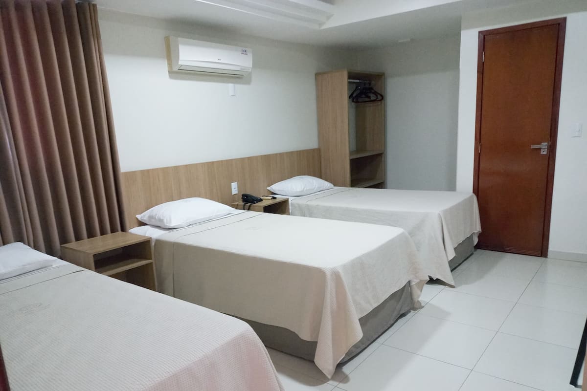 Une chambre d’hôtel avec deux lits, une armoire, un appareil de climatisation et une porte.