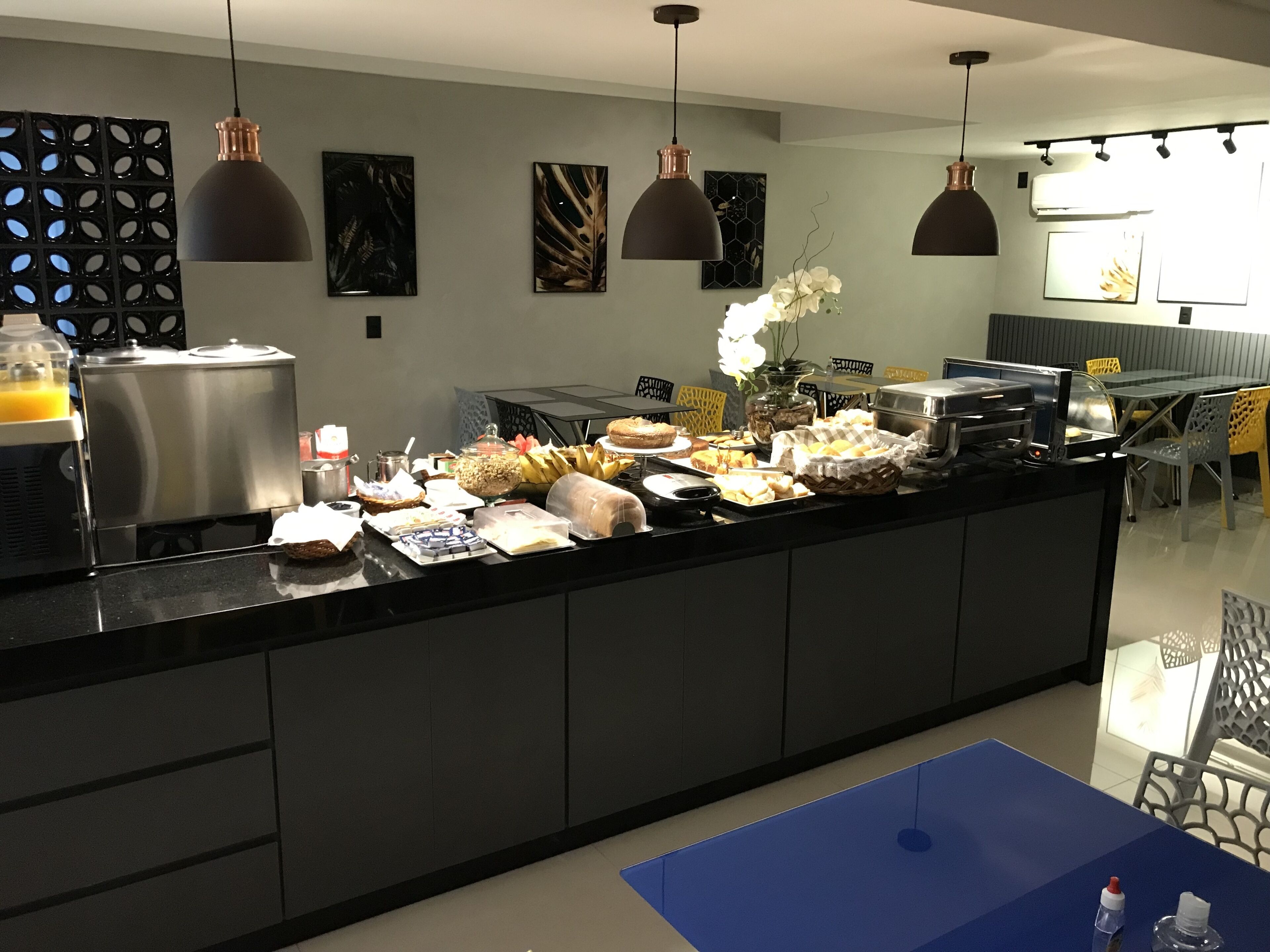 Ett modernt kök med en bufféuppställning, med bland annat ett kylskåp i rostfritt stål, en kaffemaskin och olika livsmedel placerade på bänkskivan.