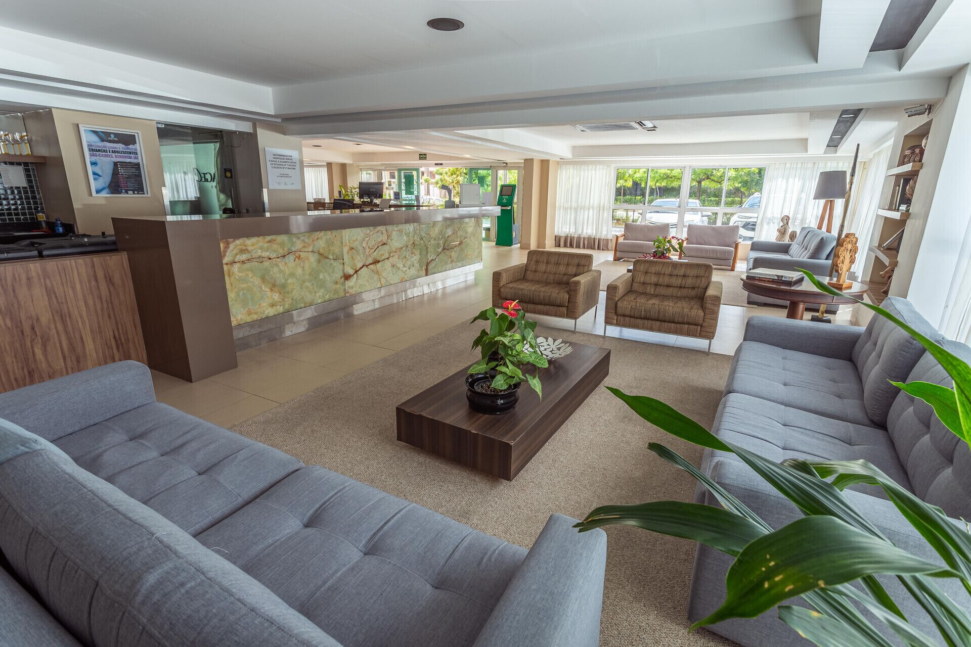 Un vestíbulo de hotel con recepción, zona de estar y vistas al exterior.