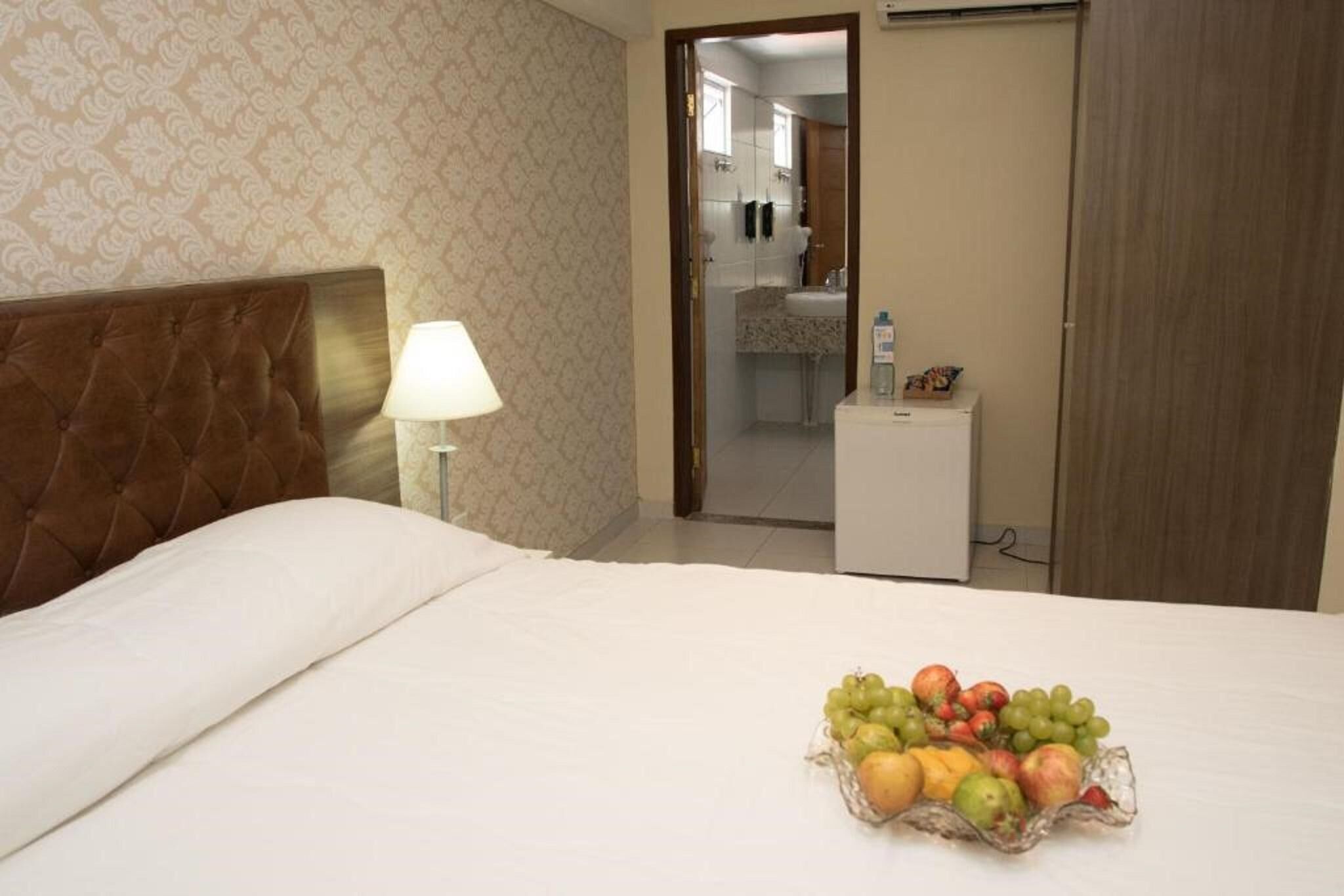 Een hotelkamer met een bed, een bedlamp en een fruitmandje op het nachtkastje.