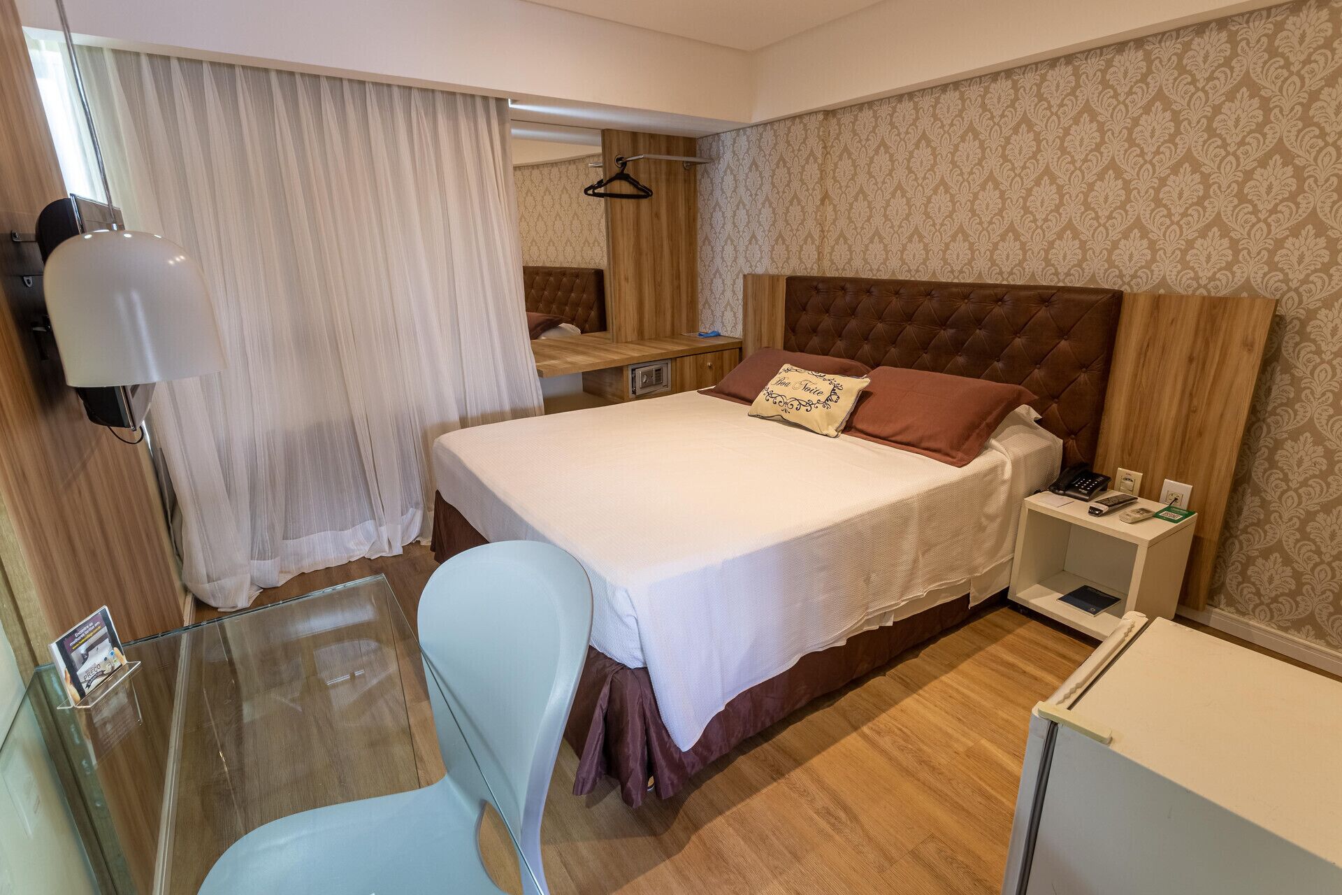 Een hotelkamer met een bed, nachtkastjes, een stoel, een bureau en een kapstok.