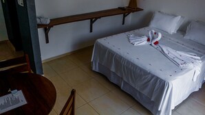 Una habitación de hotel con una cama, una estantería de madera, una mesa con un menú y una silla.