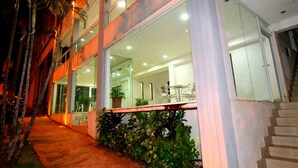 Un edificio moderno con ventanas de vidrio, un camino de hormigón y una escalera que conduce a un nivel superior.