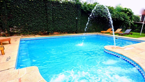 Una piscina rectangular con borde azul, rodeada por un suelo de baldosas.