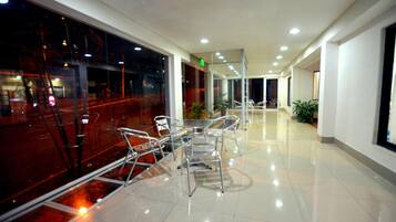 Un vestíbulo de hotel moderno con un separador de vidrio, una recepción y una zona de estar con sillas.