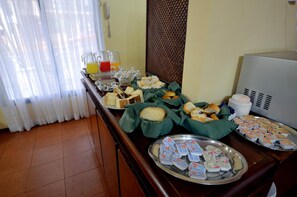 A buffet table with various food items and condiments, including bread, pastries, and dairy products.