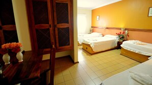 Habitación de hotel con dos camas, un armario de madera y una mesa de comedor con flores.