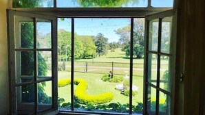 A room with a large window offering a view of a well-maintained garden with manicured lawns and trees. - Hotel Apartur Mar del Plata (Mar del Plata)