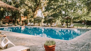 A swimming pool with lounge chairs and a potted plant. - Hotel Apartur Mar del Plata (Mar del Plata)