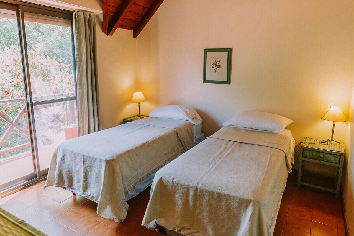 A room with two beds, a window, and a wooden ceiling.