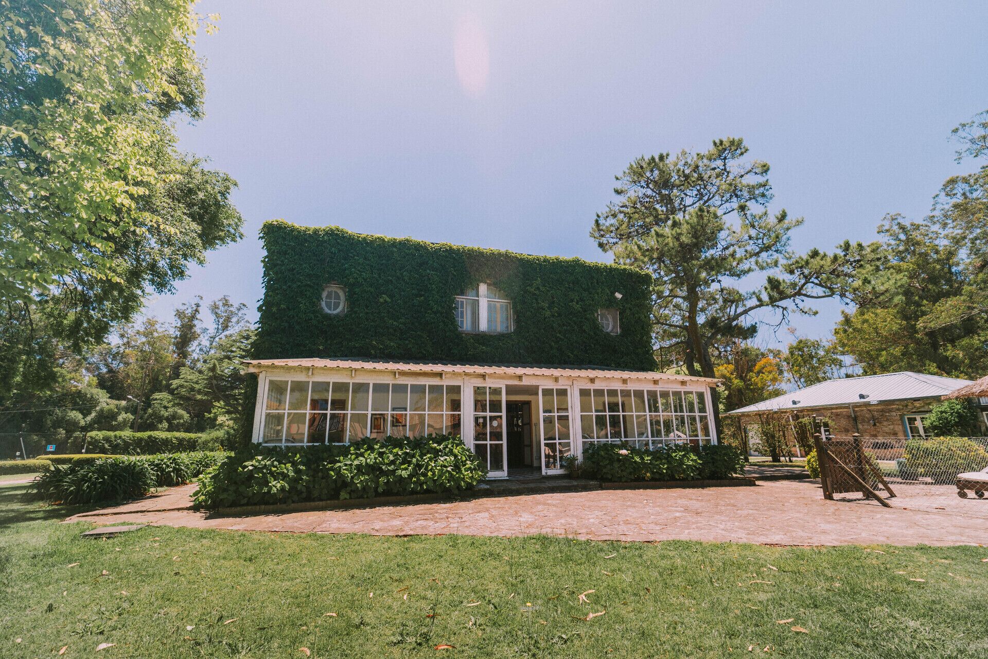 A two-story building with a green roof, large windows, and a covered porch.