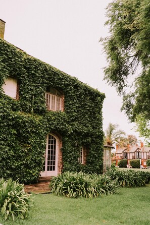 Un bâtiment recouvert de lierre, une porte et une pelouse bien entretenue.