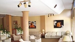 A hotel lobby with a central column, multiple seating areas, and artwork on the walls. - Hotel Morales (San Clemente)
