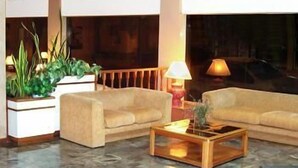 A modern lobby with a sofa set, a coffee table, and a potted plant. - Hotel Morales (San Clemente)