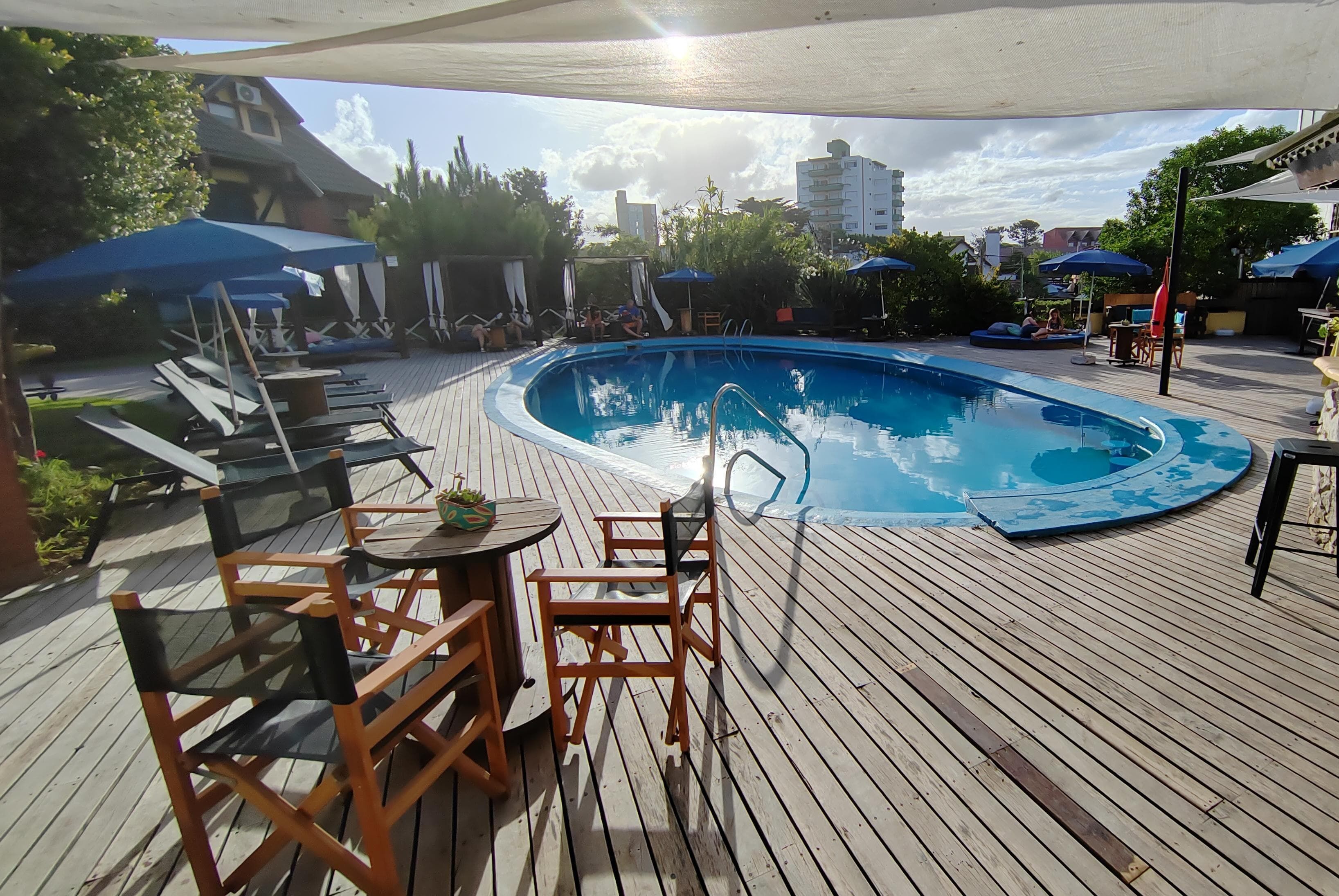 A wooden deck with a pool, lounge chairs, and umbrellas.