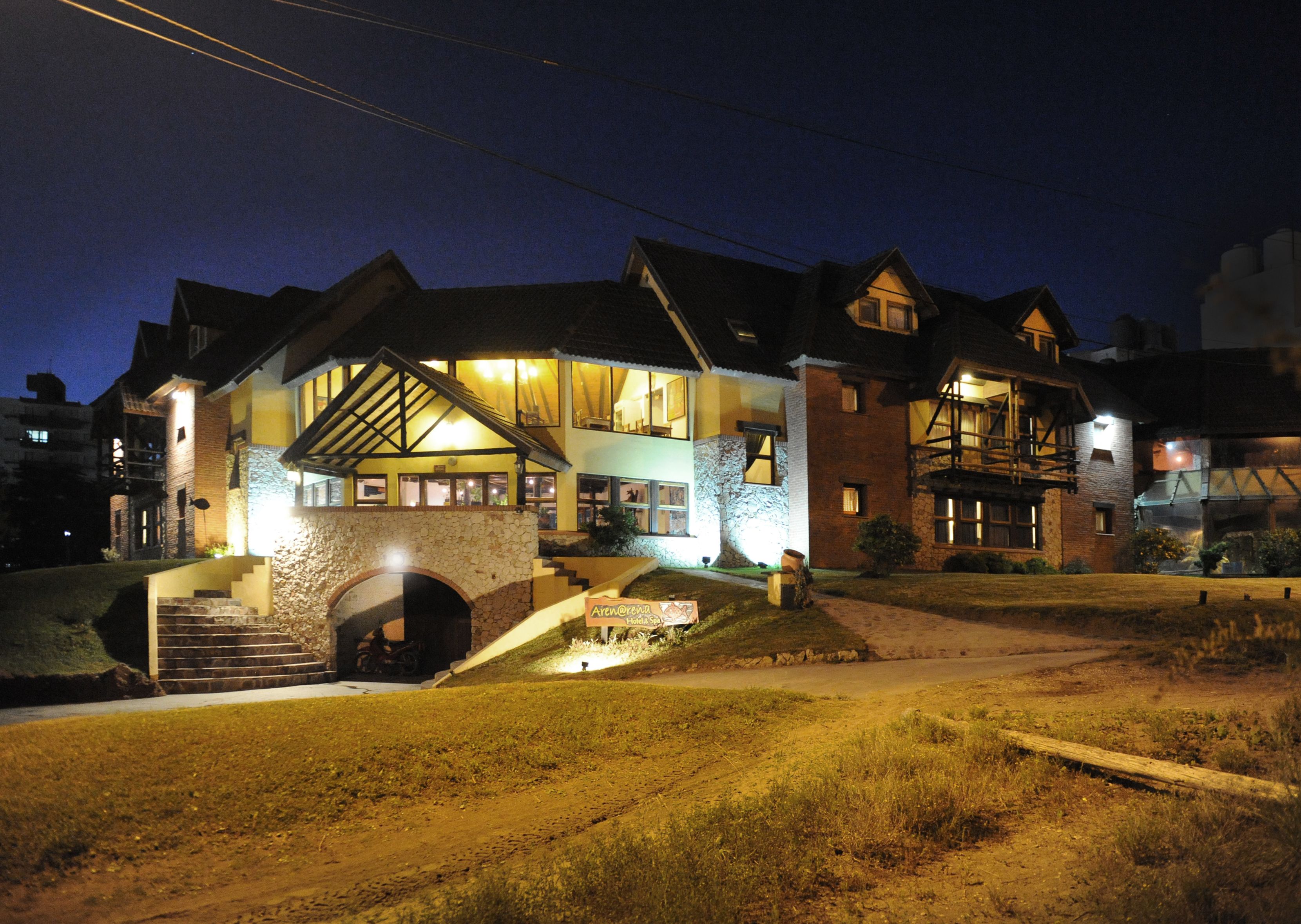 A large, multi-story house with a stone facade, multiple windows, and a well-lit entrance.