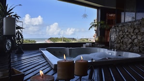 A spa area with a hot tub, candles, and a view of the ocean.