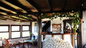 A rustic interior with a stone fireplace, wooden beams, and a stone wall.