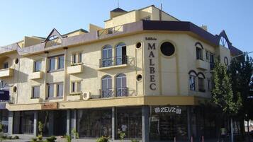 A multi-story building with the name 'Malbec' prominently displayed. It features balconies, large windows, and a flat roof.