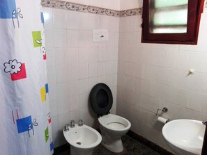 Casa de banho com duas sanitas, um bidé, uma pia e uma janela com painel de vidro jateado.