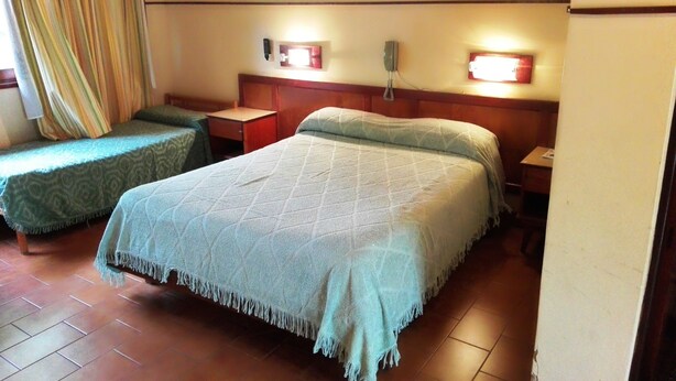 A hotel room with two single beds, a wooden headboard, bedside tables, and a telephone. - Hosteria La Cabaña (Puerto Iguazú)