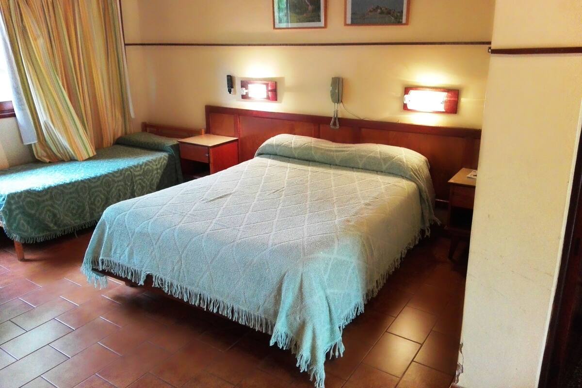 A hotel room with two single beds, a wooden headboard, bedside tables, and a telephone.