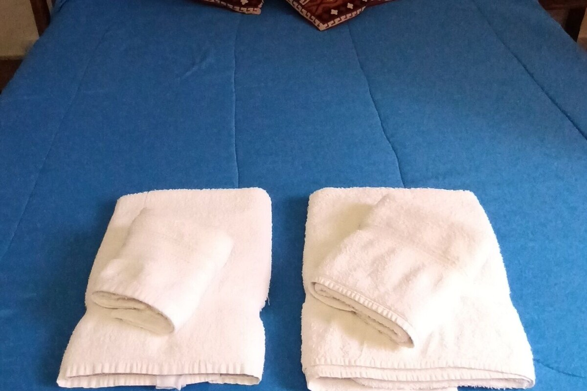 A bed with a blue mattress and two white towels folded at the foot.