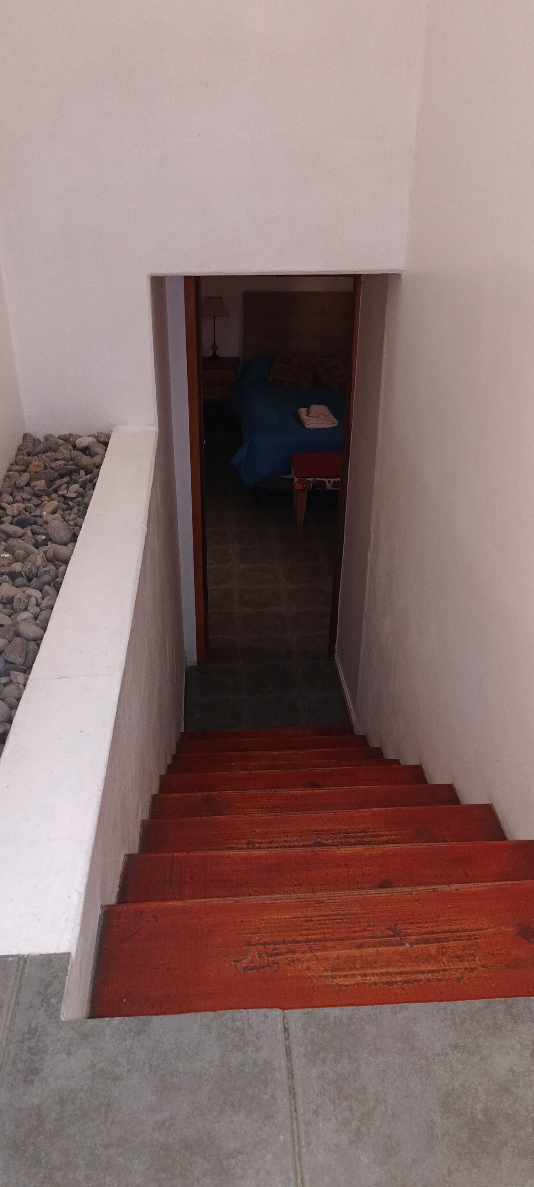 Escada que leva a um quarto com uma cama e um criado-mudo.