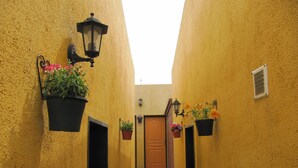 Un callejón estrecho con paredes amarillas, faroles negros y plantas en macetas.