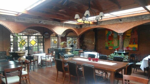 A restaurant with wooden tables and chairs, brick arches, and a chandelier. - Del Pomar Hotel Boutique (Resistencia)