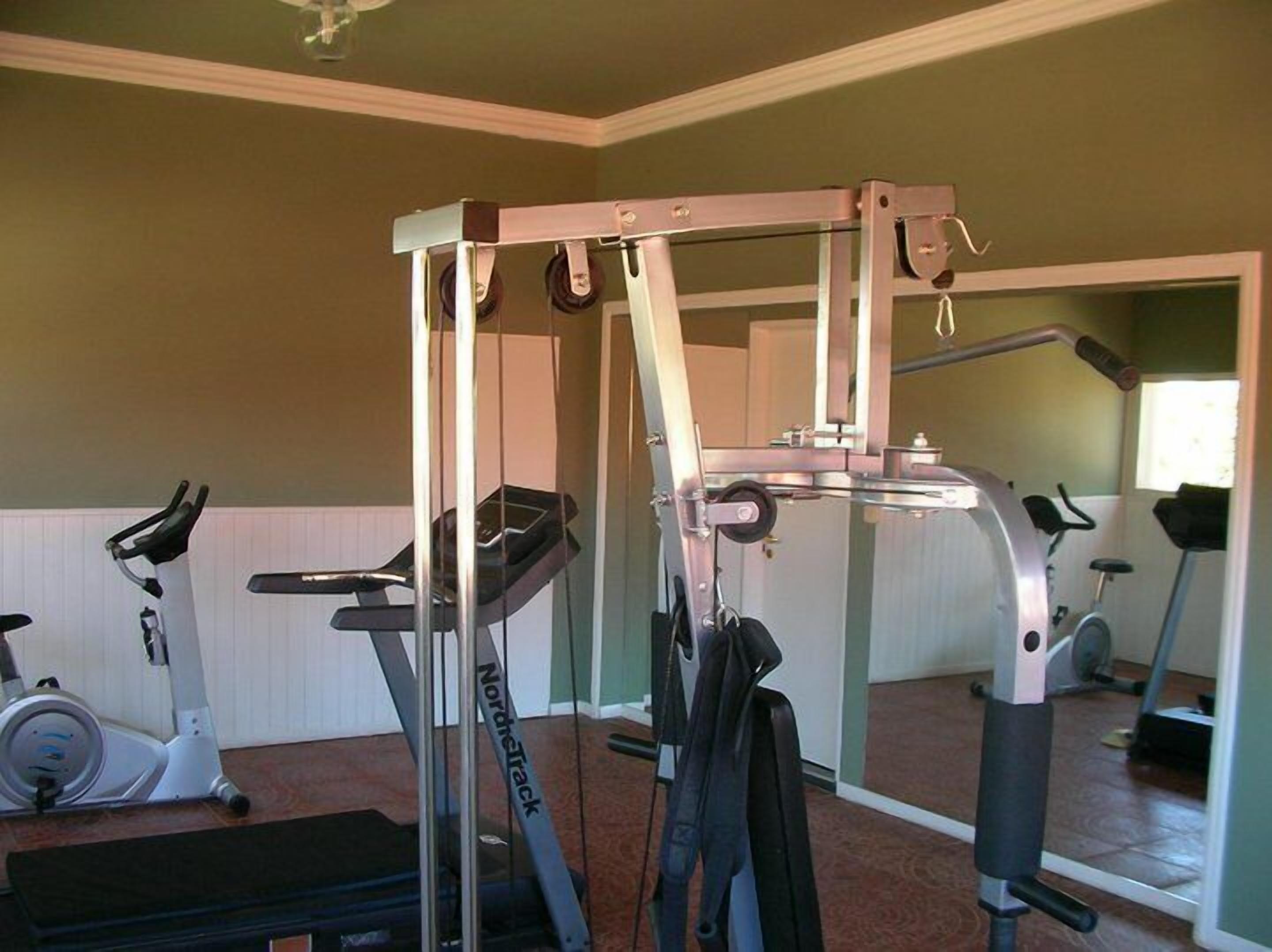 A home gym with a treadmill, stationary bike, and a NordicTrack elliptical.