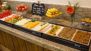 Um buffet com diversas frutas, legumes e sobremesas.