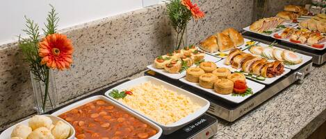 Un bufé con diversos platos, incluyendo pasta, ensaladas y pan.