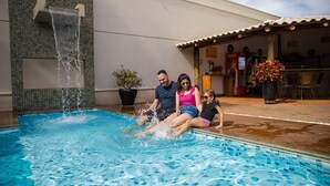 Piscina com cascata, área de estar ao ar livre e refrigerador Coca-Cola.