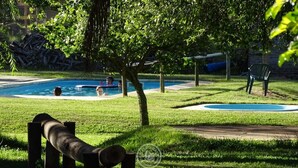 A pool area with two swimming pools, a large tree, and a wooden structure. - Hosteria del Pescador (Punta del Diablo)