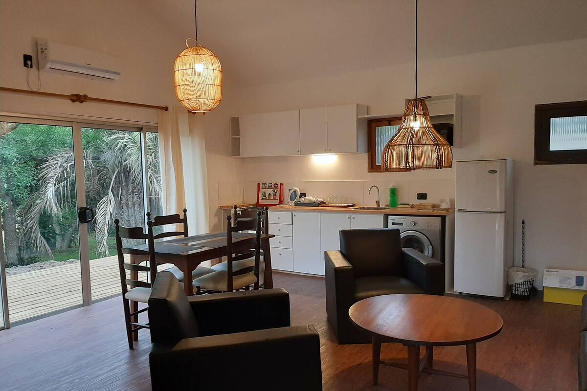 Une cuisine moderne avec des meubles blancs, un lave-linge encastré et un coin repas comprenant une table et des chaises en bois.