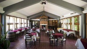 A spacious dining area with high ceilings, brick walls, and large windows. Tables are set with white tablecloths and chairs. - Hosteria del Pescador (Punta del Diablo)