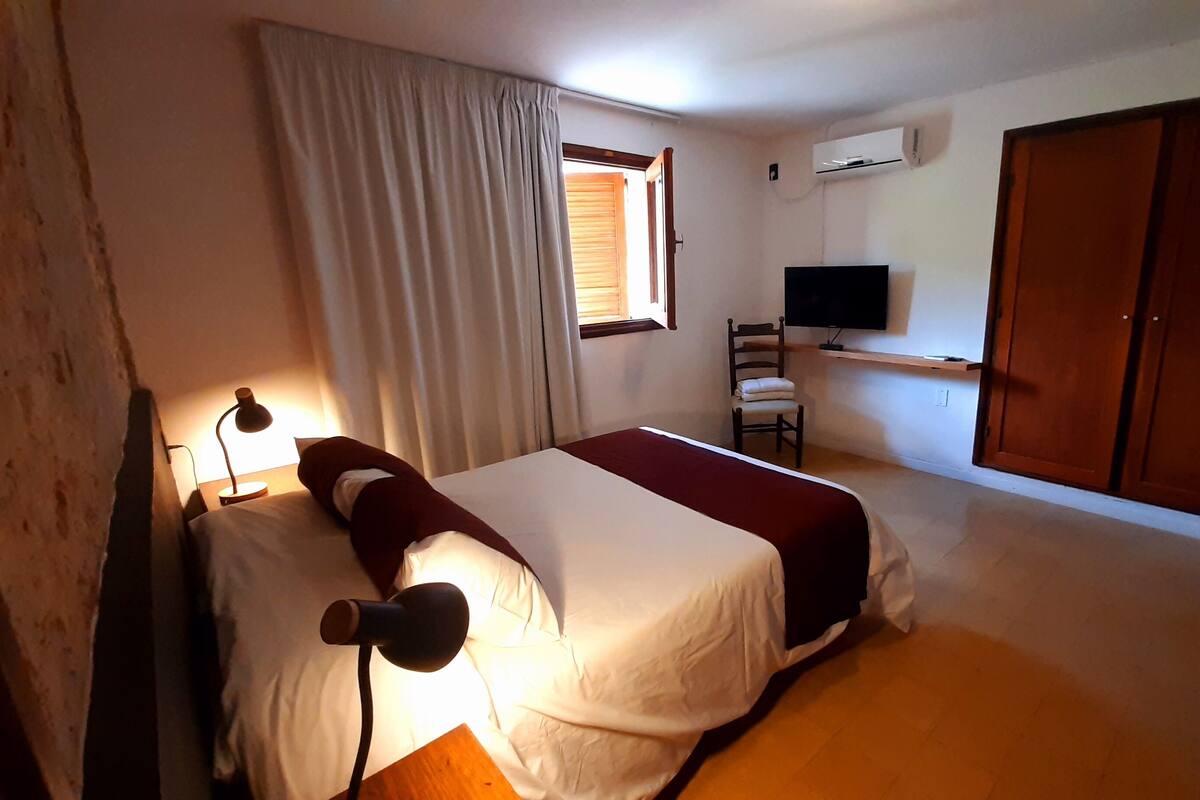 Une chambre à coucher avec un lit, une chaise, un téléviseur et une armoire.