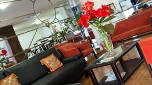 A modern interior with a black sofa, red chairs, and a glass table with a vase of red flowers. - Hotel del Sol (Córdoba)