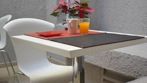 A white table with a red placemat, a glass of orange juice, and a potted plant with pink flowers. - Hotel del Sol (Córdoba)