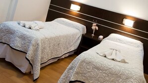 Two single beds with patterned bedding and a nightstand with a vase of flowers. - Hotel del Sol (Córdoba)