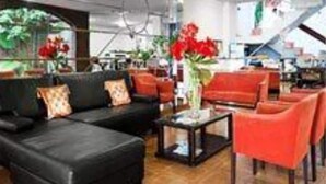 A modern interior with a black sofa, red chairs, and a glass coffee table. - Hotel del Sol (Córdoba)