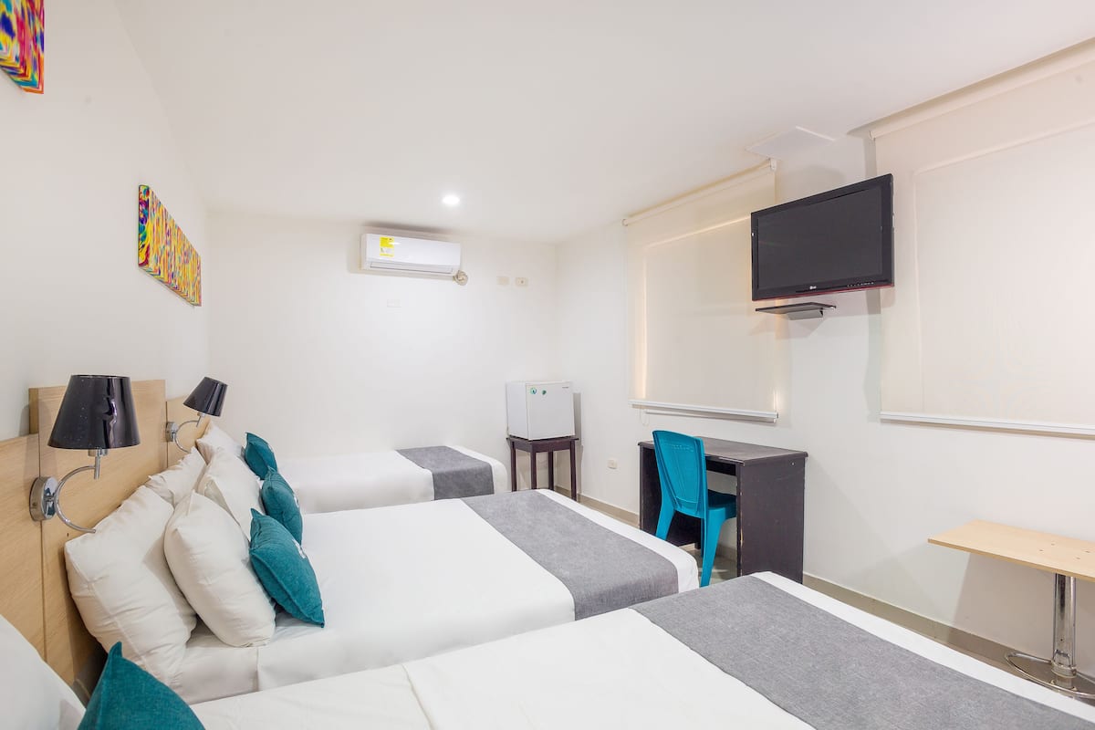 Une chambre d’hôtel avec deux lits, un bureau, une chaise, une télévision et un appareil de climatisation.