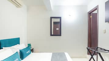 A hotel room with a bed, a nightstand, a mirror, and a door.